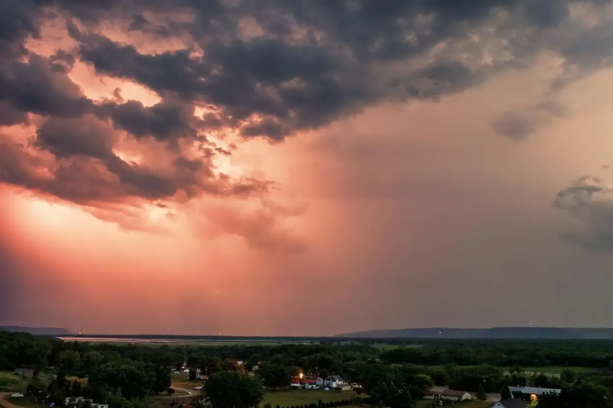 A breathtaking aerial view of Nelson, WI during sunset with dramatic clouds and vibrant sky hues.