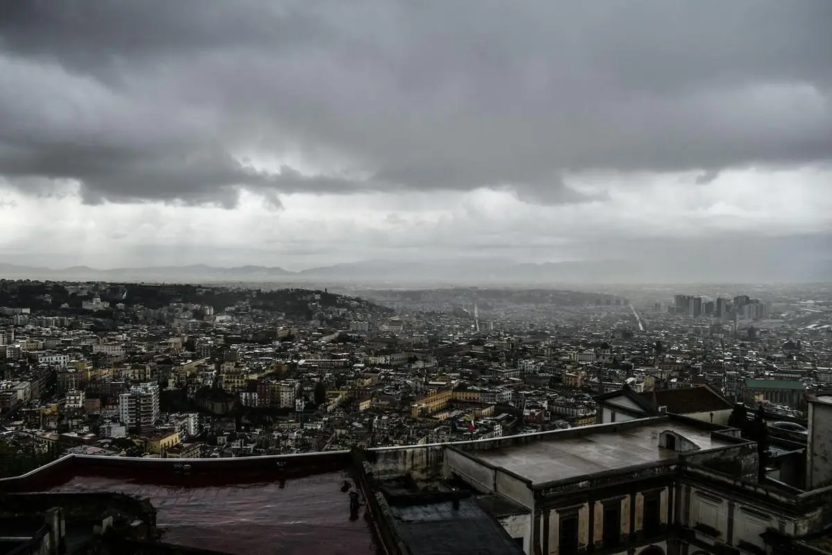 Moody cityscape of Naples under a cloudy sky, capturing the urban sprawl and architecture.