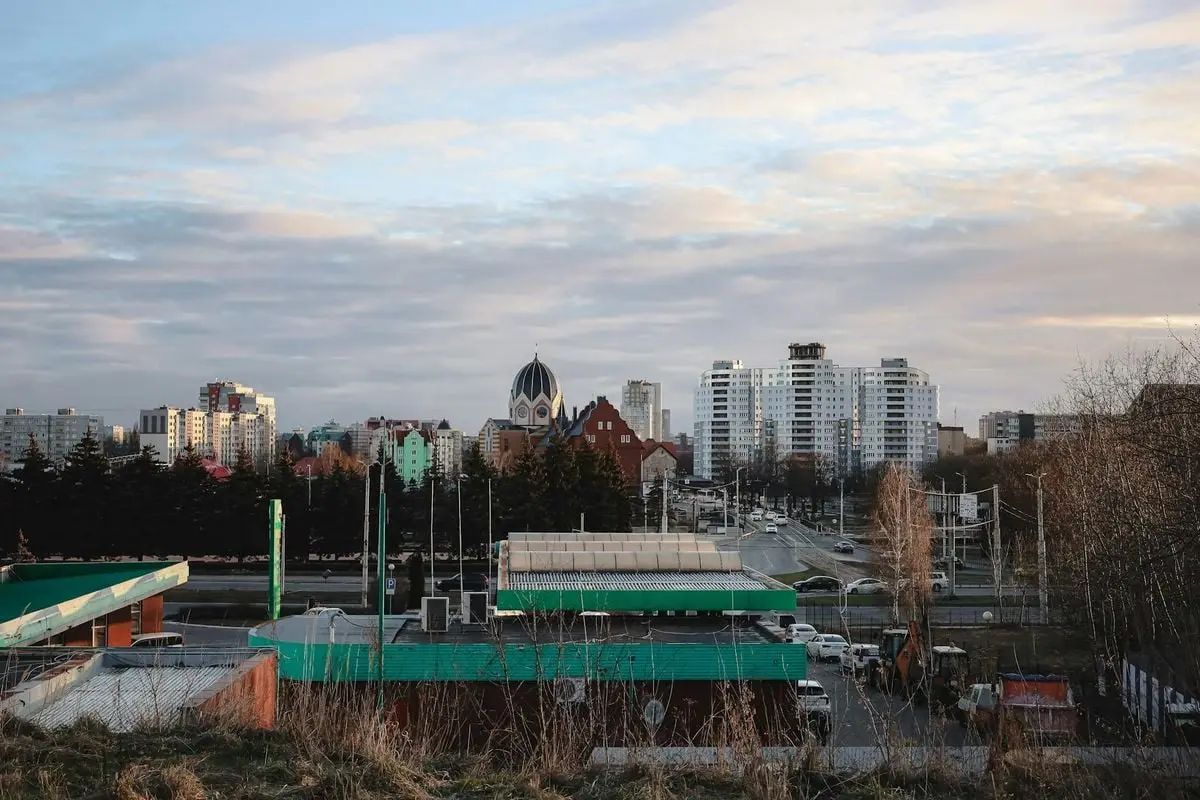 A cityscape featuring a mix of architectural styles under a cloudy sky at dusk.