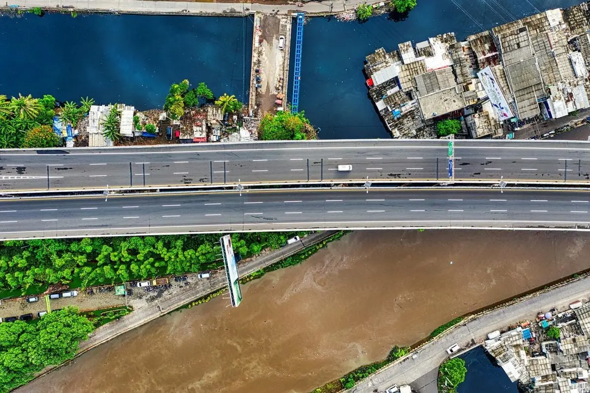 Aerial view of a highway over a river in Jakarta, showcasing urban infrastructure.