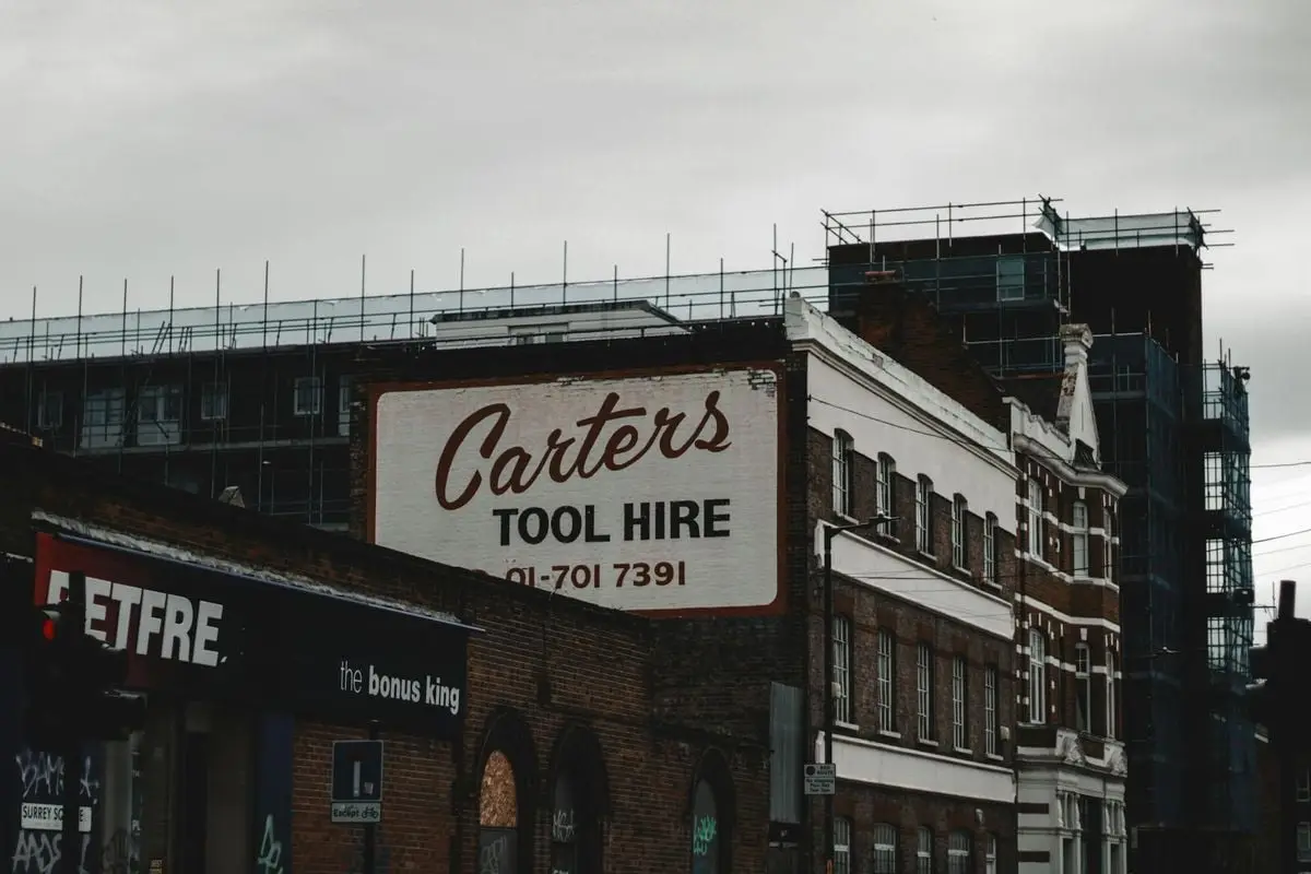 An atmospheric view of Carter's Tool Hire billboard on Old Kent Road, London under cloudy skies.
