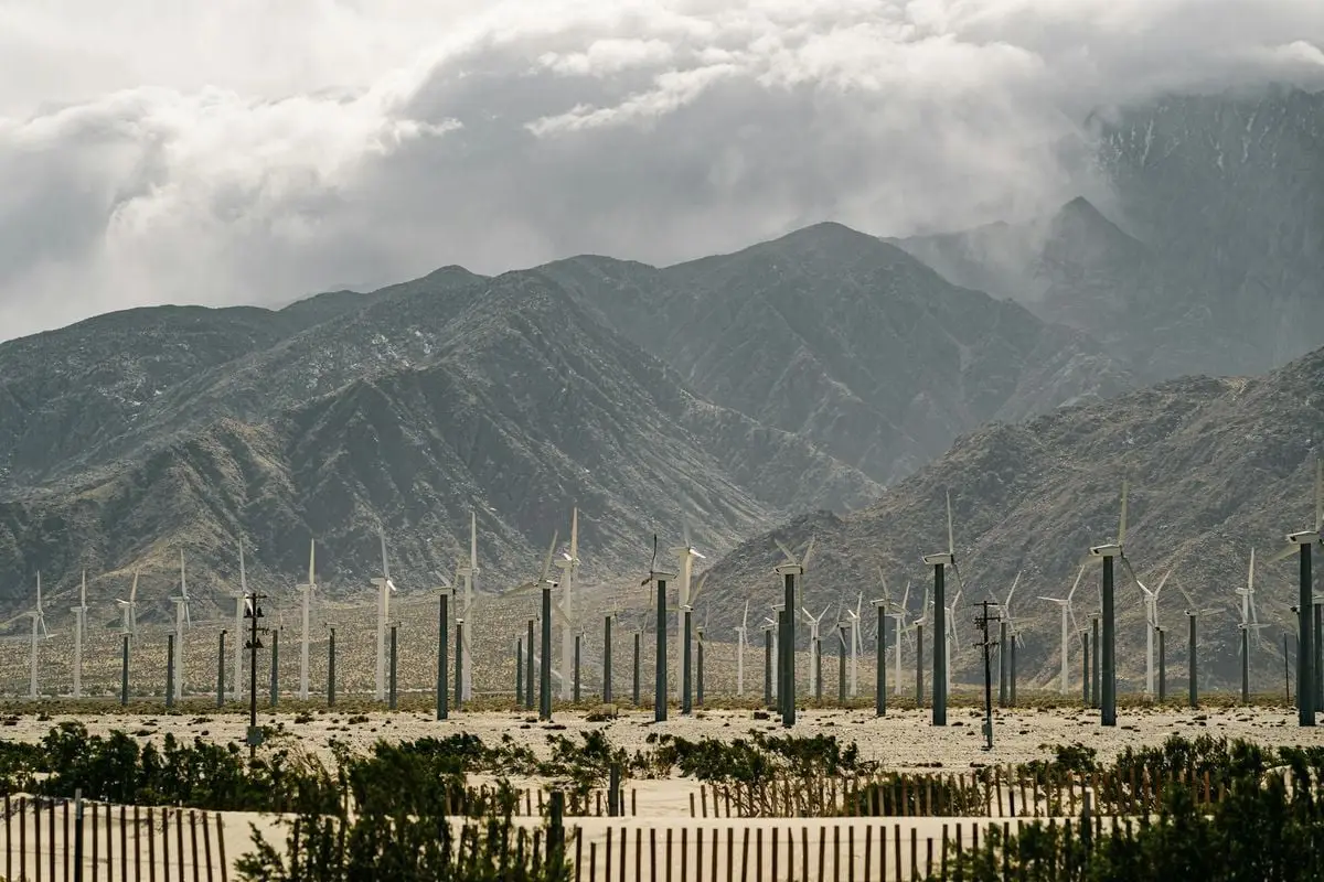 Majestic mountains with an array of wind turbines harnessing renewable energy on a cloudy day.