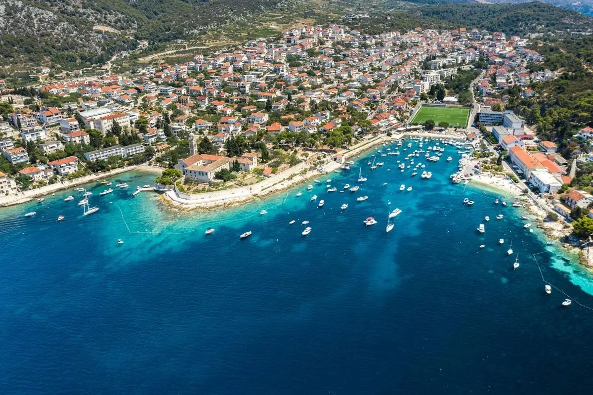 A stunning aerial shot of a coastal Croatian town with boats in the clear blue Adriatic Sea on a sunny day.