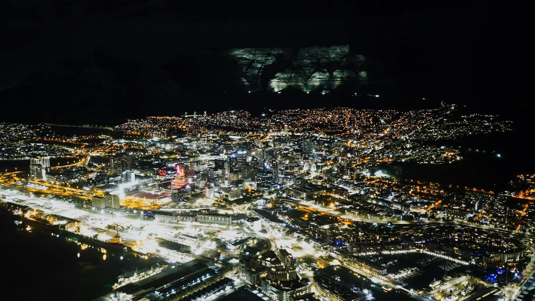 Stunning night aerial view of Cape Town city lights with majestic Table Mountain in the background.