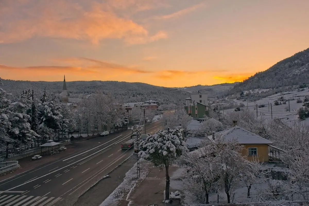 A picturesque winter sunset over a snow-covered village street in Bucak, Burdur, Türkiye.