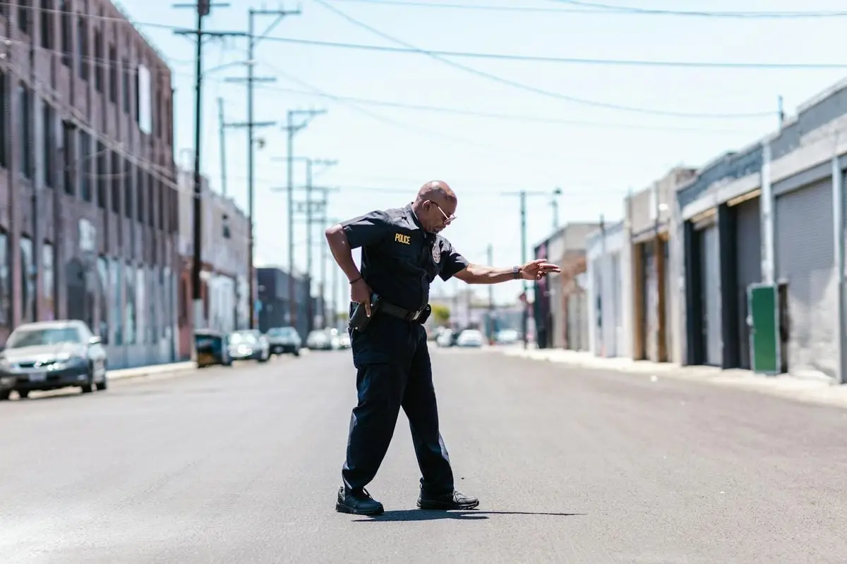 A police officer poses confidently on a sunny urban street. Perfect for law enforcement themes.