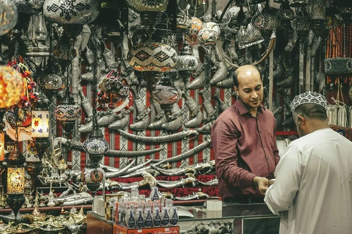 A bustling Omani market stall filled with traditional lamps and daggers, showcasing vibrant culture.