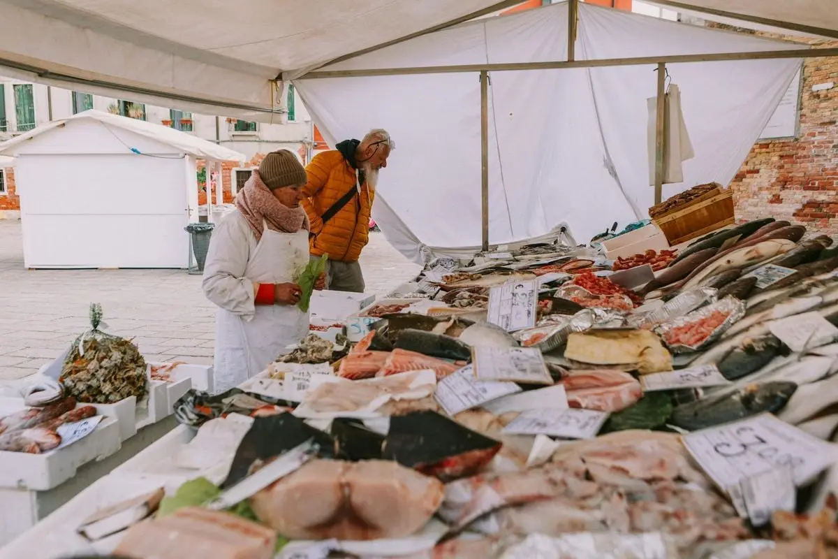 Explore a bustling fish market with diverse seafood options in a quaint Italian setting.
