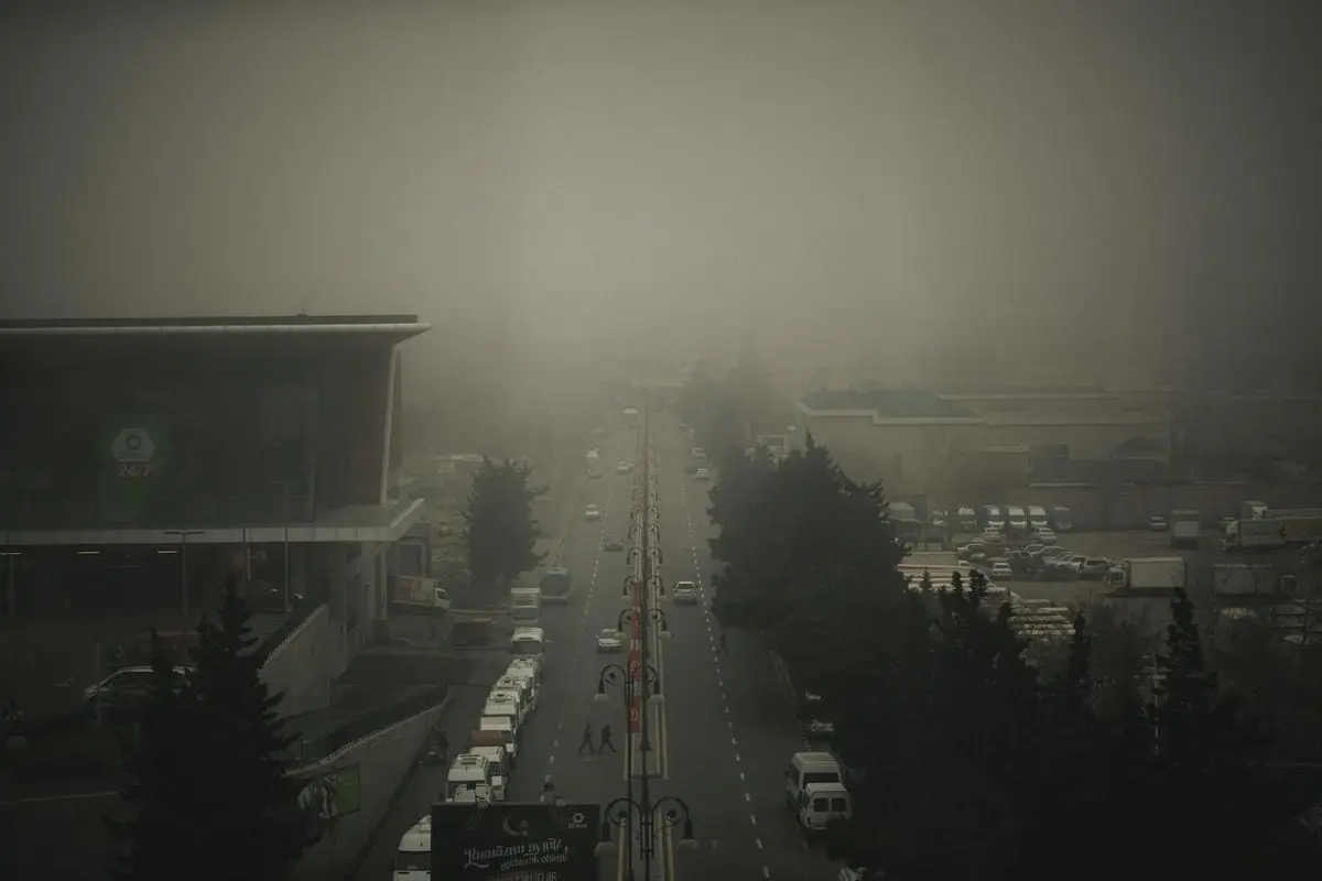 A foggy day in Baku, Azerbaijan, showcasing an urban road with heavy traffic and towering buildings.